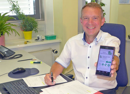 Carsten Bauerochse präsentiert auf einem Smartphone die Ideen- und Beschwerde-App der Stadt Salzgitter