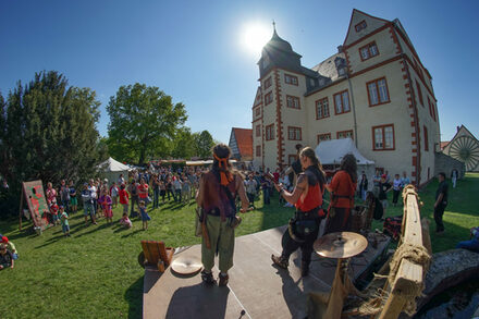 Das Bild zeigt eine mittelalterliche Musikgruppe, die vor Besucherinnen und Besuchern beim Museumsfest im Garten des Schlosses Salder aufspielen.