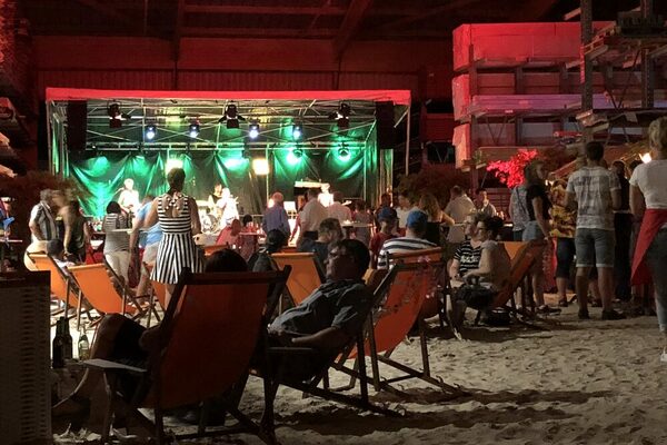 Menschen sitzen in Strandkörben vor einer Bühne.