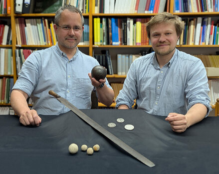 Museumsleiter Arne Homann (links) und Bezirksarchäologe Tobias Uhlig (rechts) präsentieren Funde aus der Zeit des Dreißigjährigen Krieges