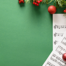 Notenblätter mit Weihnachtskugeln und grünem Zweig auf grünem Hintergrund